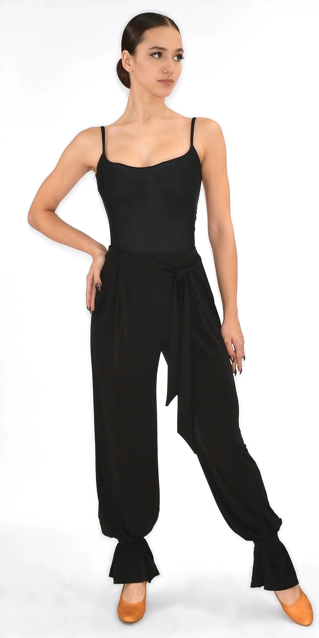 Woman wearing a black sleeveless top and high-waisted pants on a white background