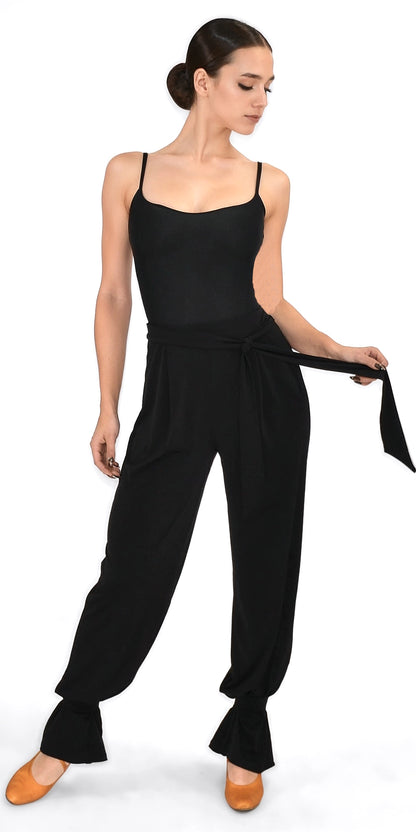 Woman wearing a black sleeveless top and high-waisted pants on a white background